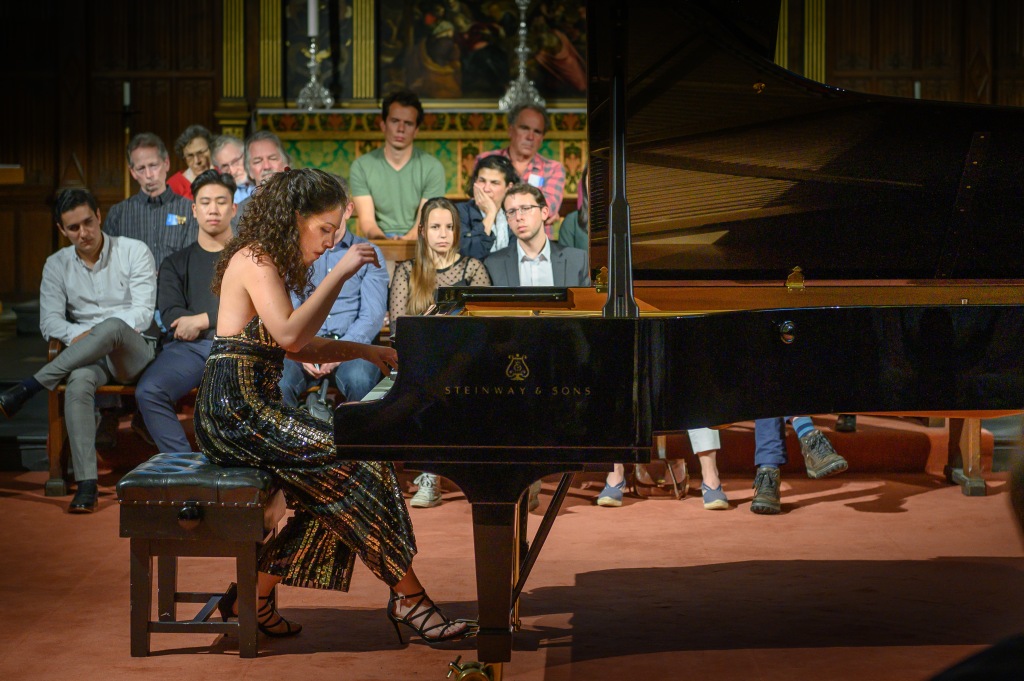 A woman playing the piano in front of an audience.